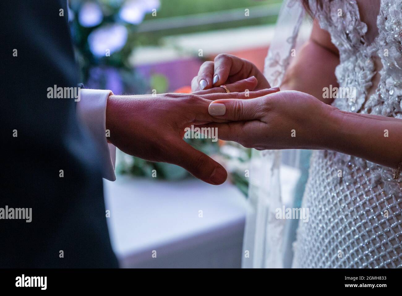A beautiful scene of bride and groom putting on their engagement rings ...