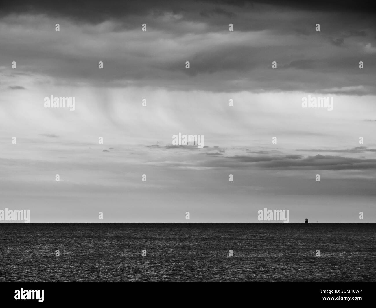 Adriatic Sea Ocean Horizon with Cargo Ship Silhouette in Grado, Italy in Monochrome Black and White Stock Photo