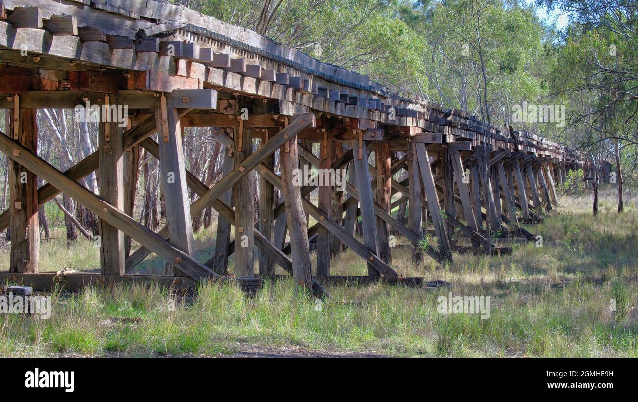 Old wooden railway trestle bridge in dappled morning light near Narrandera Stock Photo
