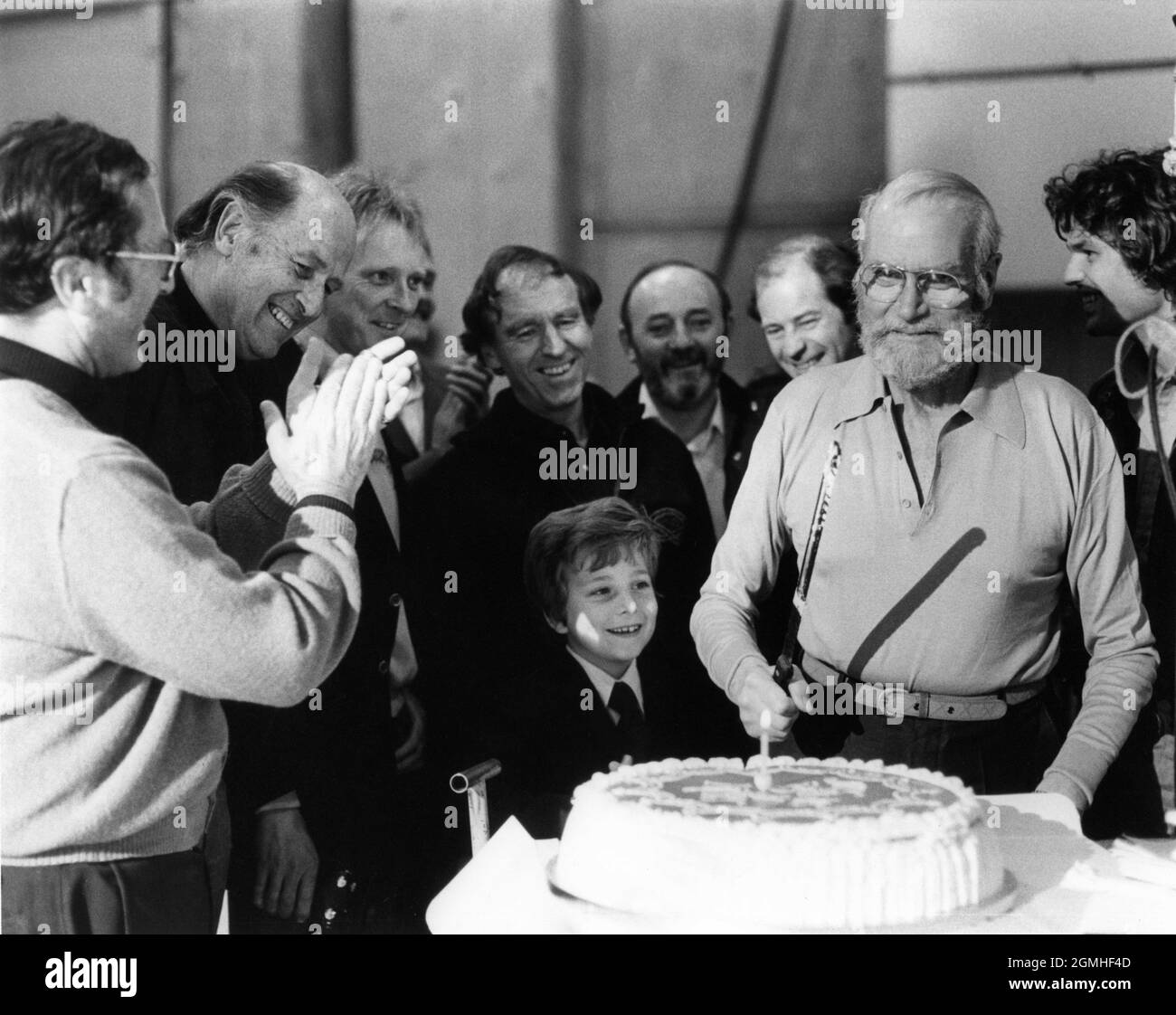 LAURENCE OLIVIER celebrates his 72nd Birthday on May 22nd 1979 with from left CHARLES H. SCHNEER RAY HARRYHAUSEN Director DESMOND DAVIS JAXON GWILLIM (son of actor Jack Gwillm) and HARRY HAMLIN on set candid during filming of CLASH OF THE TITANS 1981 director DESMOND DAVIS written by Beverley Cross costume design Emma Porteous creator of special visual effects (Dynamation) Ray Harryhausen music Laurence Rosenthal producers Charles H. Schneer and Ray Harryhausen Charles H. Schneer Productions / Peerford Ltd. / distribution Cinema International Corporation (CIC)  (UK) Metro Goldwyn Mayer (USA) Stock Photo