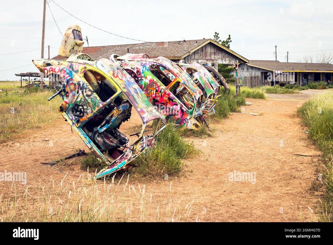 painted Volkswagen Beetles half buried at an angle at Slug Bug Ranch
