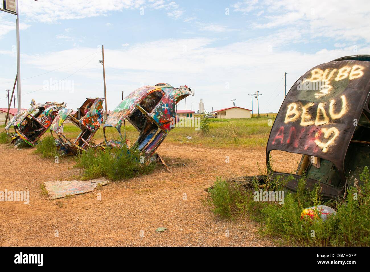 painted Volkswagen Beetles half buried at an angle at Slug Bug Ranch