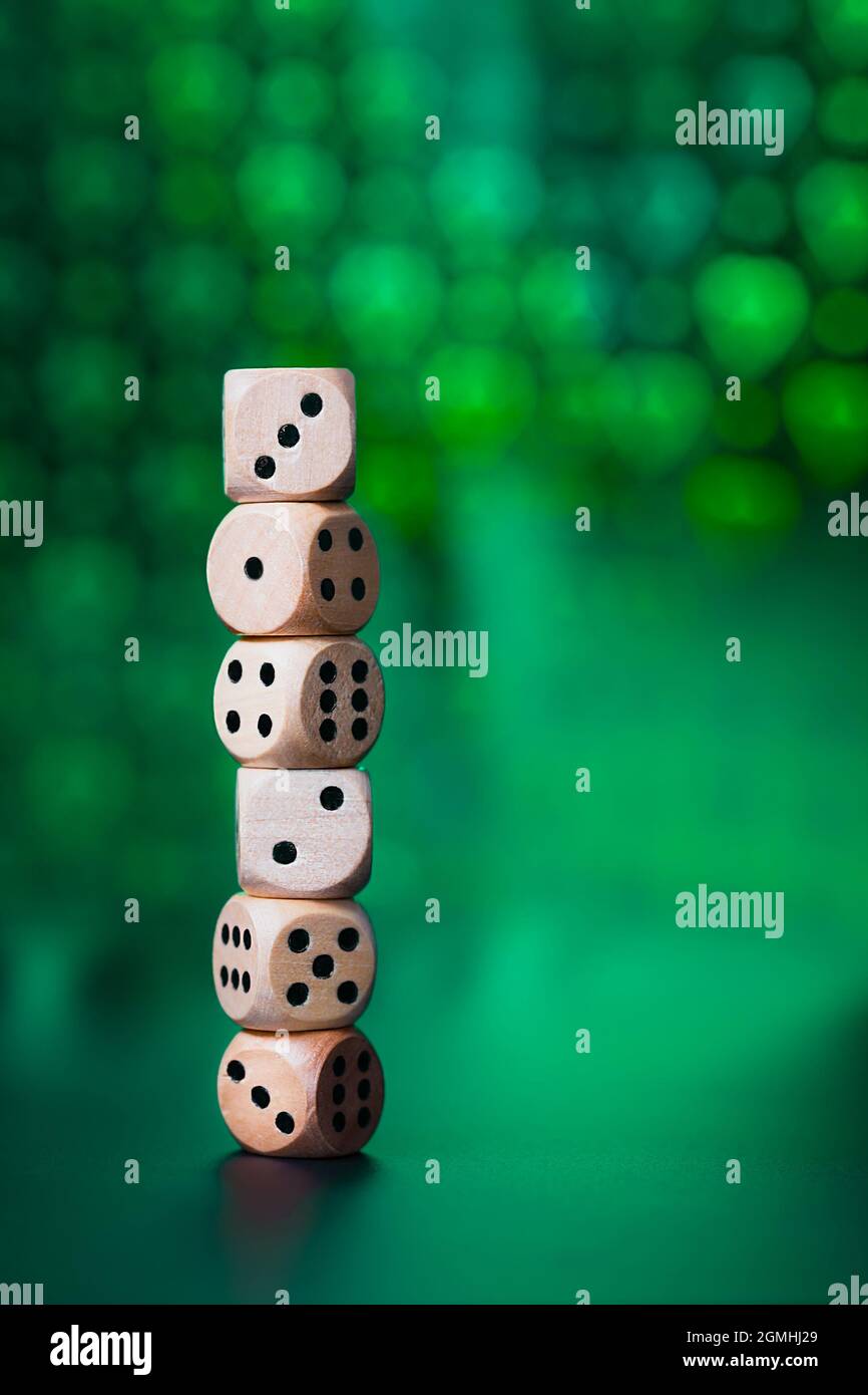 A column of dice on a green table, on a dark green blurred background in the form of hearts. Stock Photo