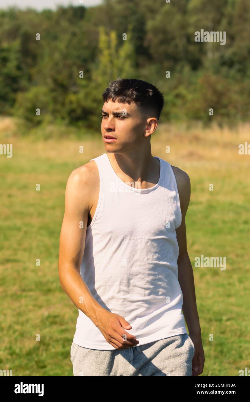 An 18 year old teen boy in a sleeveless top on a late summer's day