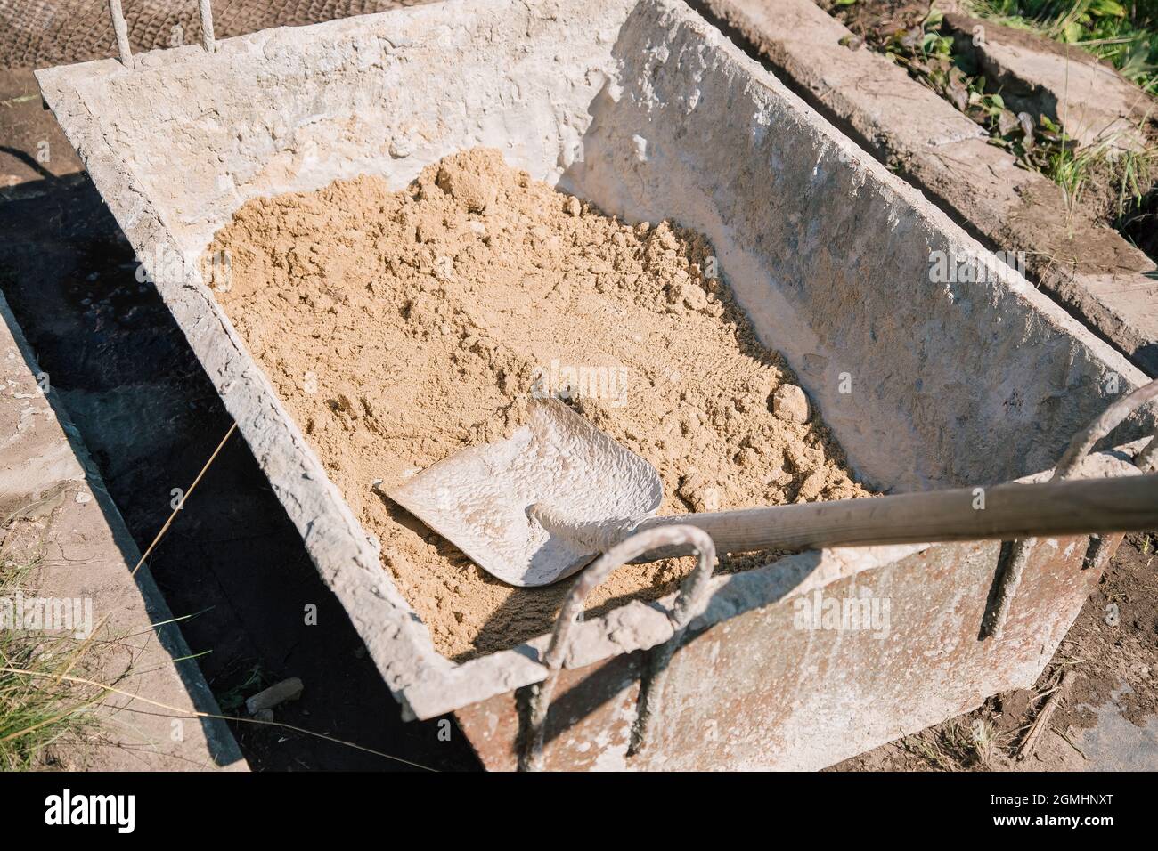 Uploading sand into a cement mixture for pouring a garden path ...