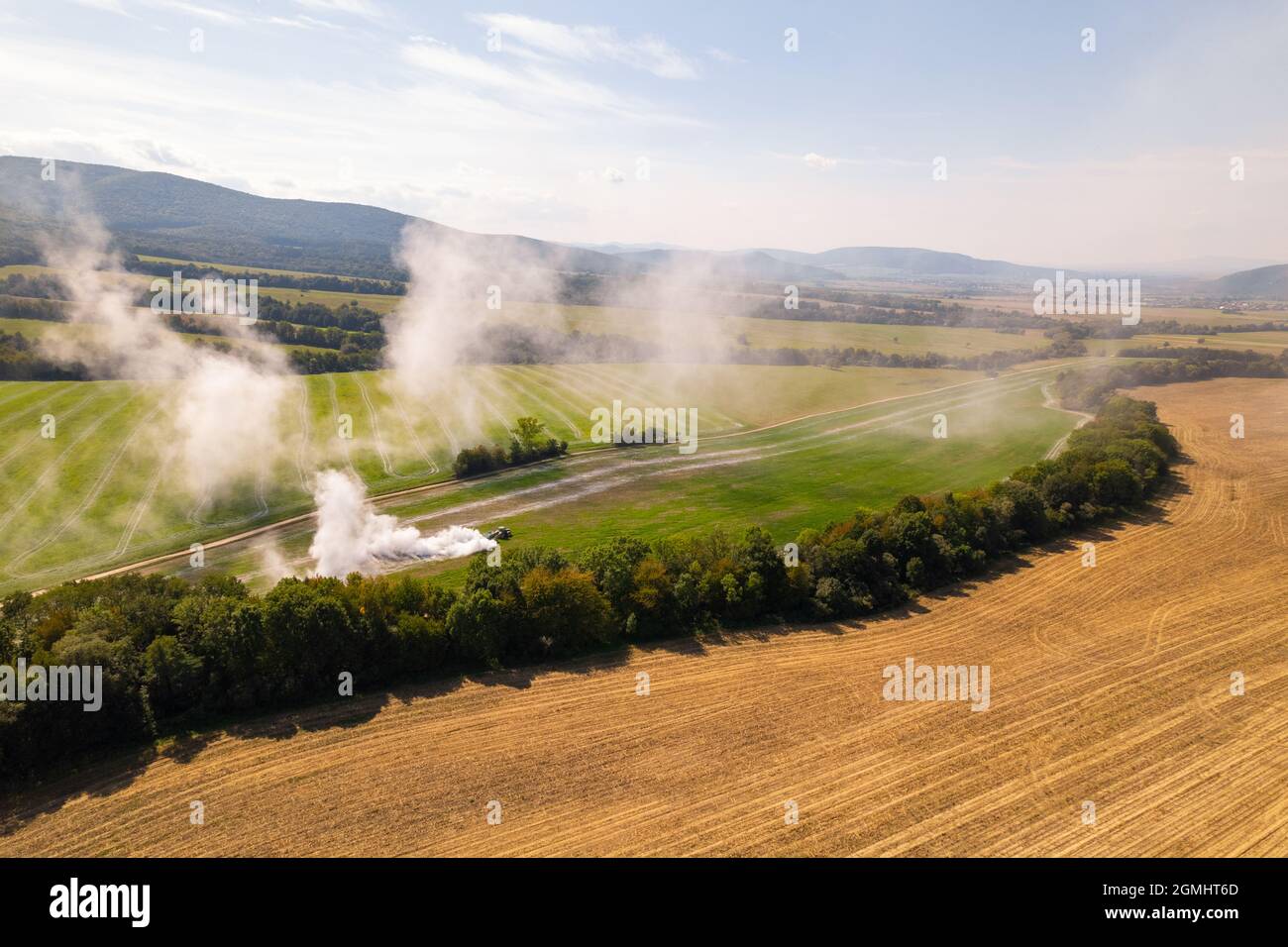 Aerial view of a tractor spreading lime on agricultural fields to