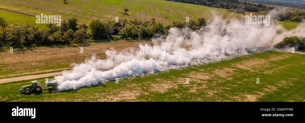 Aerial view of a tractor spreading lime on agricultural fields to