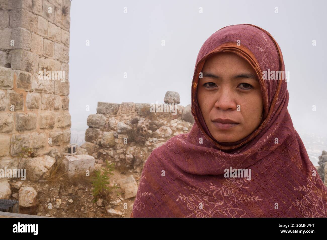 An asian lady with a scarf in front of parts of Ajloun Castle in Jordan Stock Photo