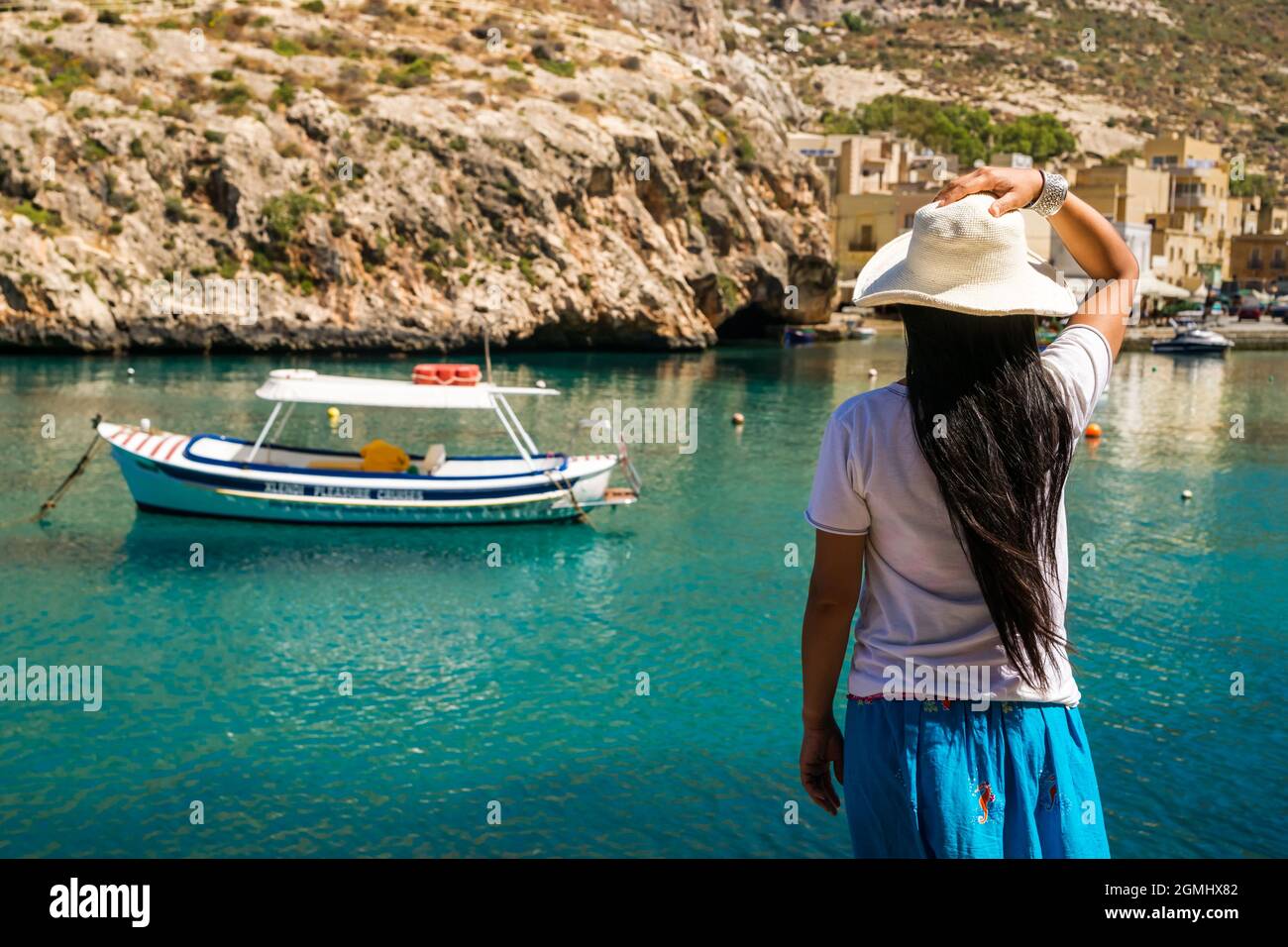 An asian lady enjoys the view over the waters of Xlendi Bay at Gozo Island, part of the maltese archipel Stock Photo