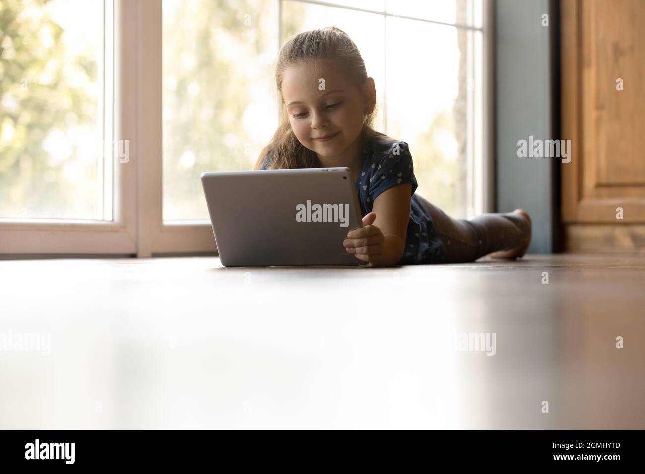 Happy adorable small child girl using digital computer tablet. Stock Photo