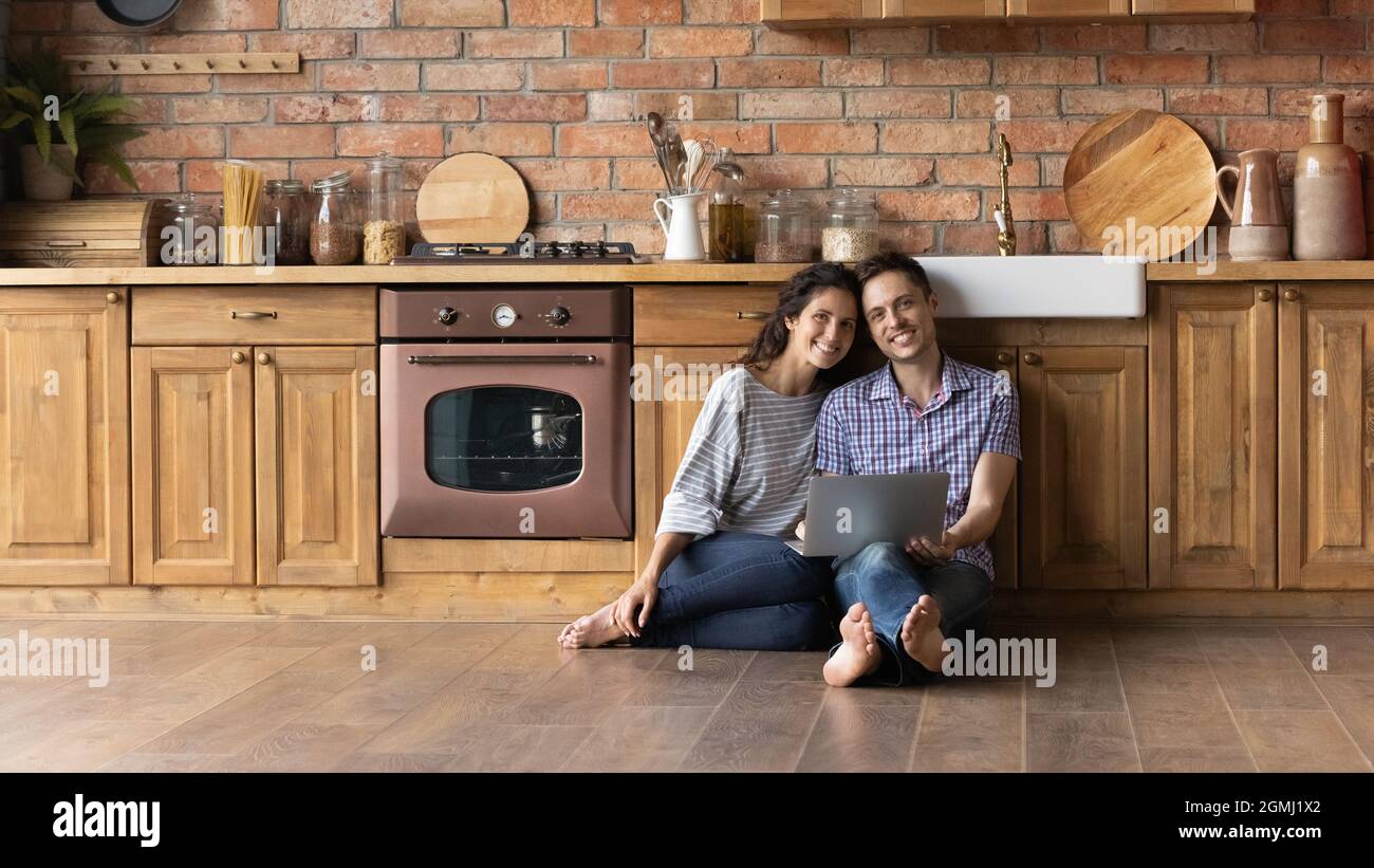 Portrait of smiling young hispanic family couple sitting on floor. Stock Photo