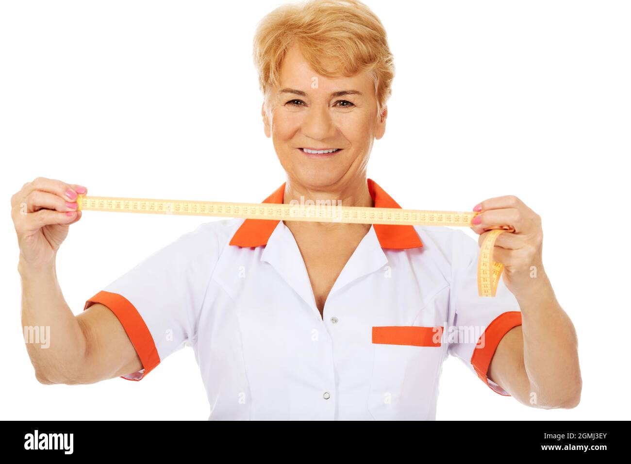 A senior female doctor wearing a white and orange uniform and holding a