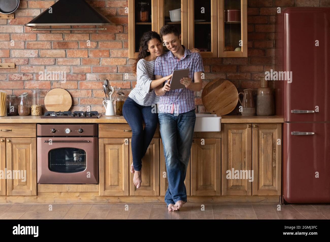 Relaxed smiling young family couple using computer tablet at home. Stock Photo