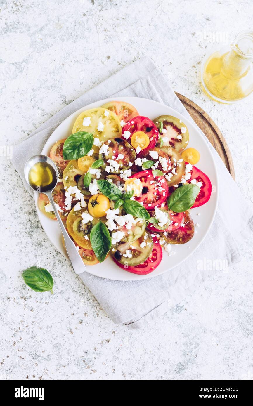 Fresh bright tomato salad from colorful tomatoes with feta cheese, basil and olive oil. Vegetarian and vegan food. Concept for a tasty and healthy mea Stock Photo