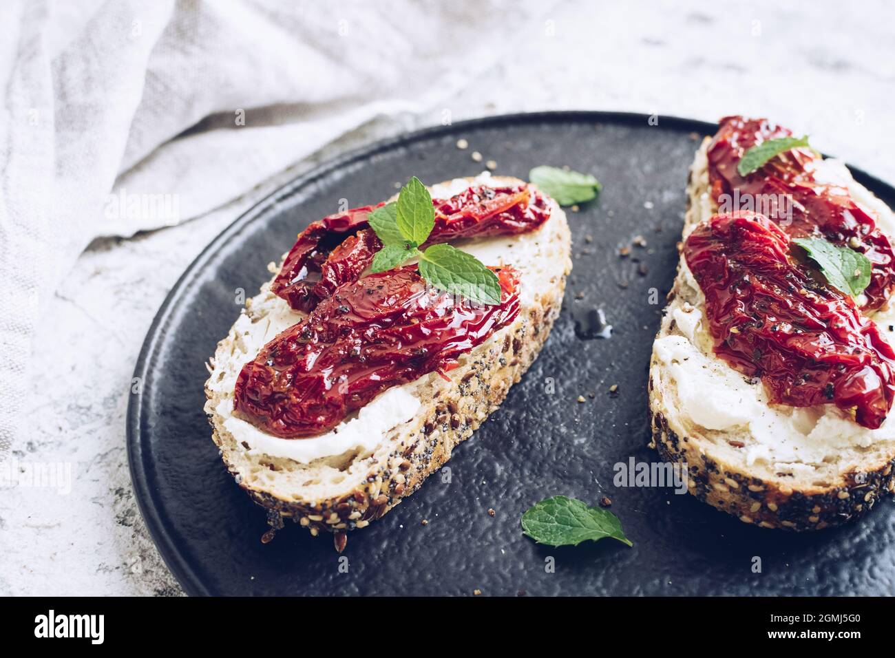 Bread slices with sun dried tomatoes, cream cheese and mint. Italian