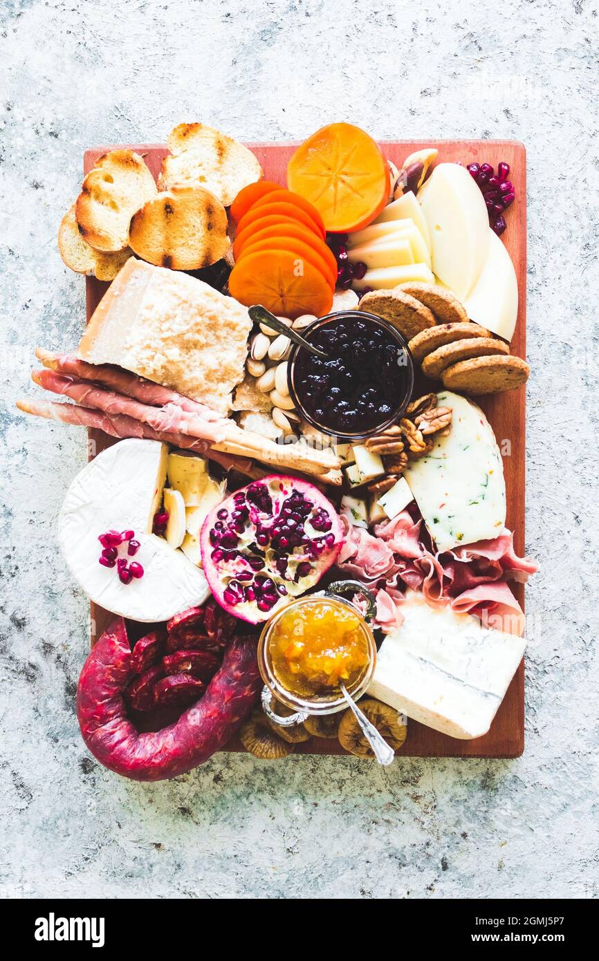 Charcuterie board. Cheese platter: Parmesan, caciocavallo, camembert and other with prosciutto, salami, fruits and nuts. Assortment of tasty appetizer Stock Photo