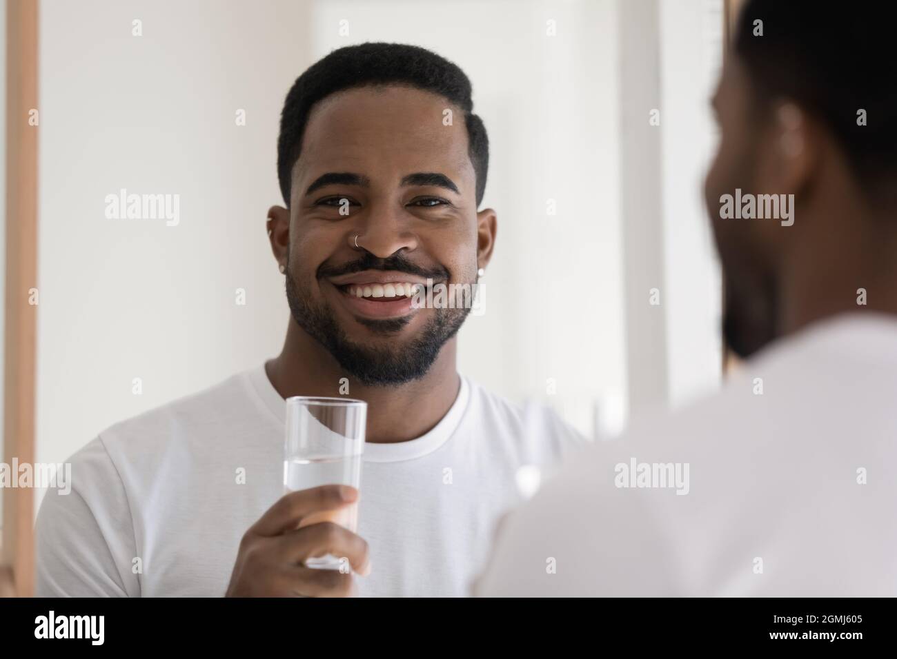 Handsome African guy holds glass of still natural water Stock Photo