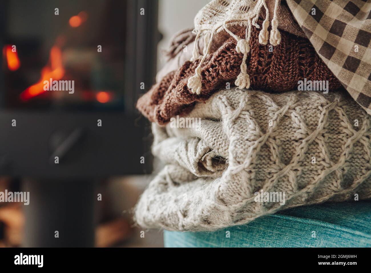 A stack of warm clothes on an armchair an iron fireplace with a Stock Photo