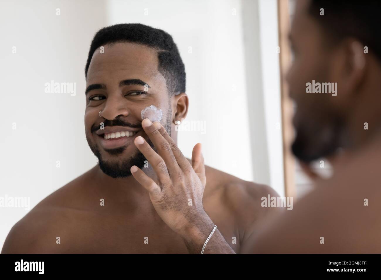 African guy applying cleanse products or facial cream on face Stock Photo