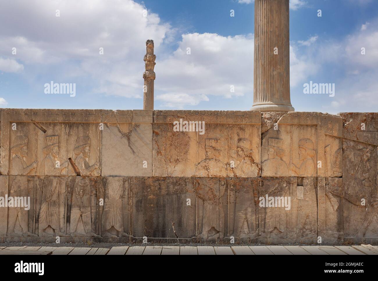 Ruins of Apadana and Tachara Palace behind stairway with bas relief carvings in Persepolis UNESCO World Heritage Site against cloudy blue sky in Shira Stock Photo