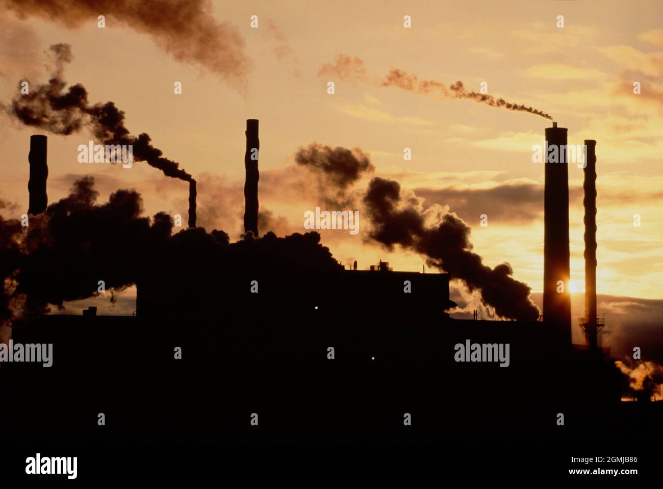 Canada. Ottawa. Heavy industry. Factory buildings and smoking chimneys silhouetted against sunset. Stock Photo