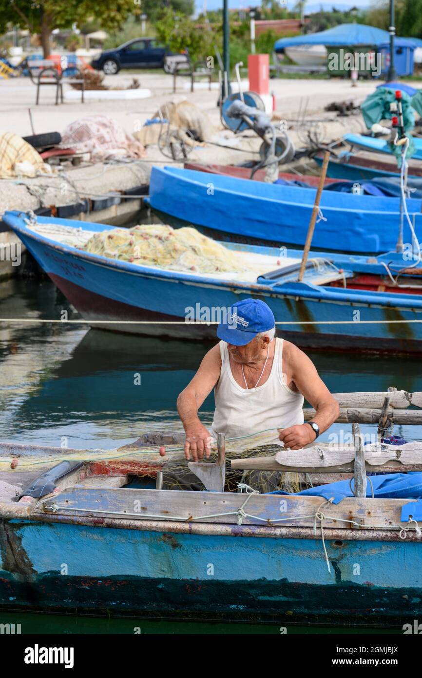 A fisherman mending his nets in the harbour at the village of Koronisia on Koronisia island in the Ambracian Gulf,  Arta Municipality, Epirus, Greece. Stock Photo