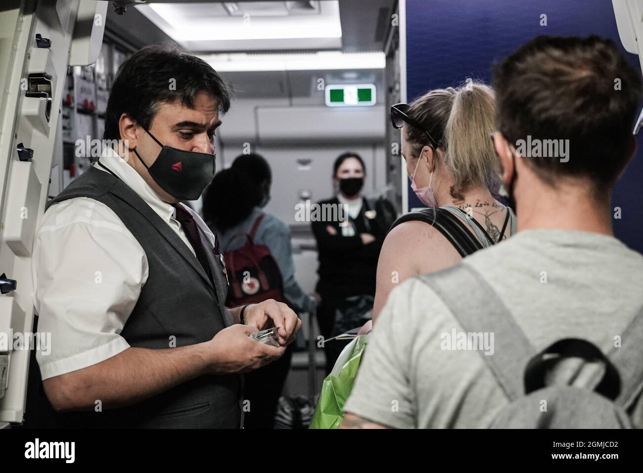 Lod, Israel. 17th Sep, 2021. A mask wearing flight attendant greets passengers as they board a