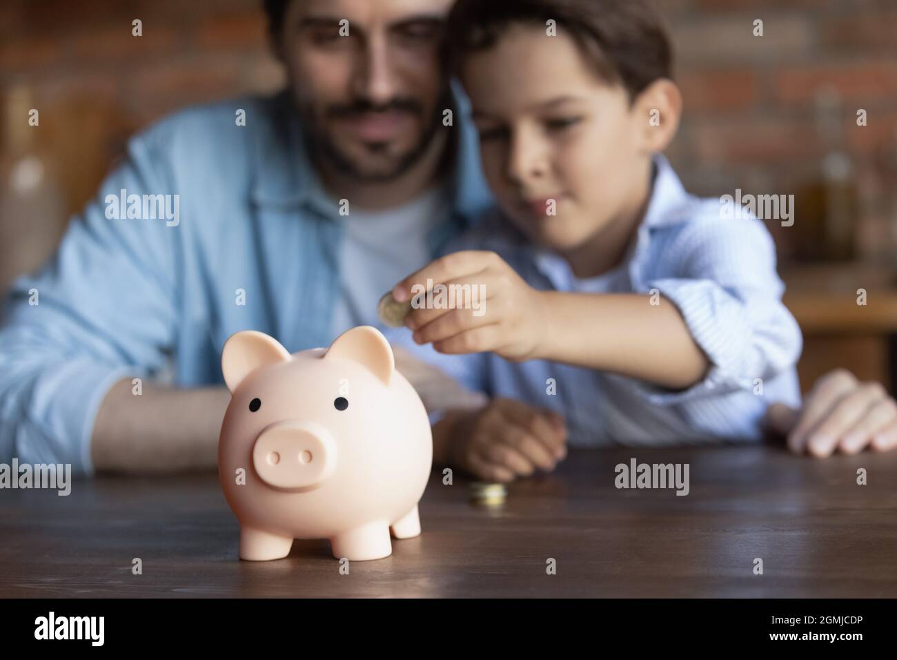 Crop close up family putting coin into pink piggy bank Stock Photo - Alamy