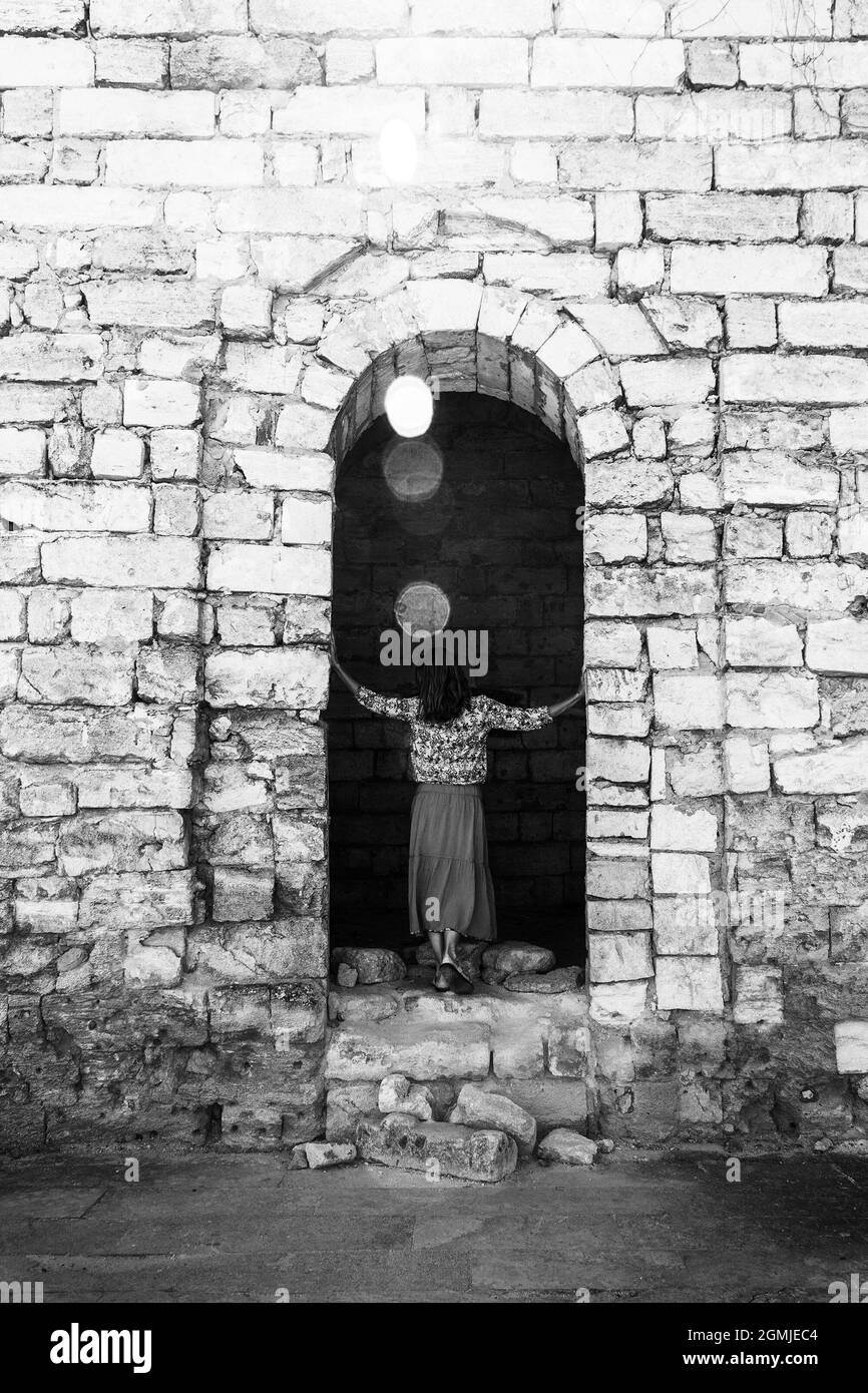 a young woman stands with her back on the ruins of an ancient fortress ...