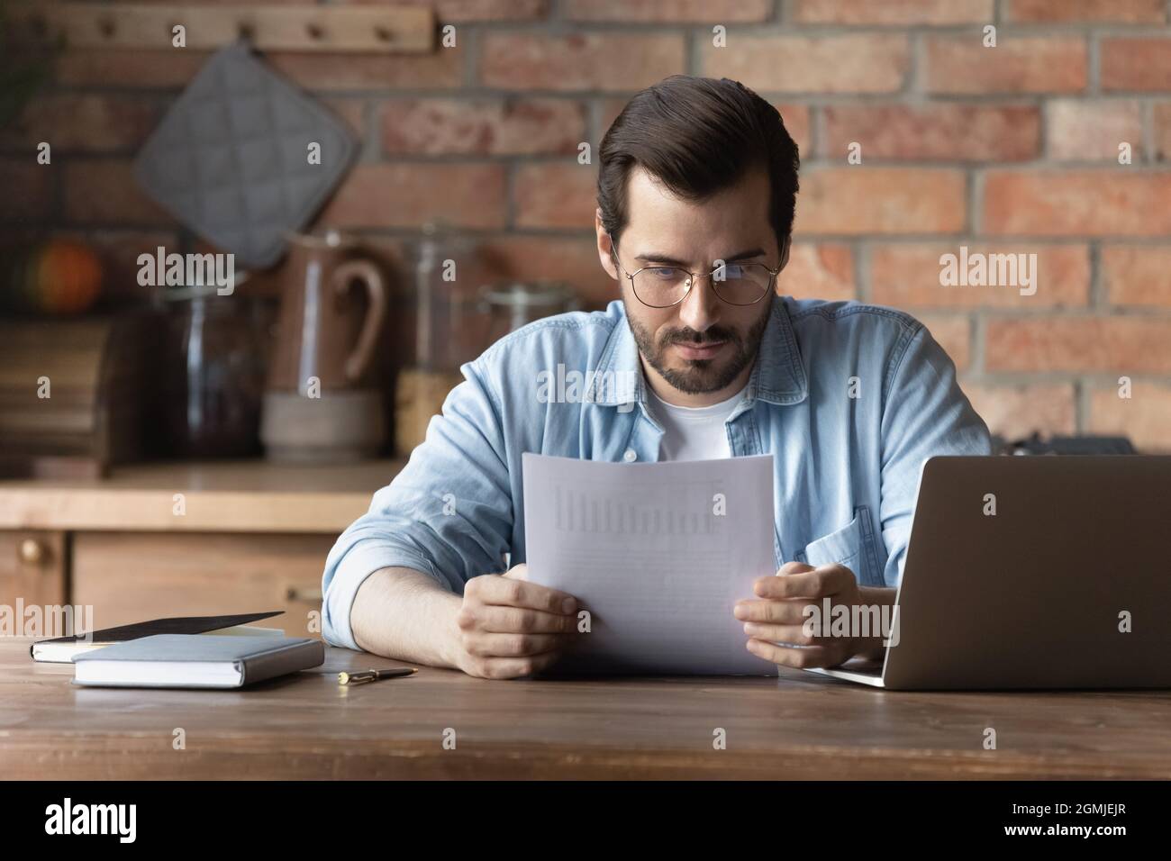 Confident man in glasses reading document, analyzing financial report Stock Photo