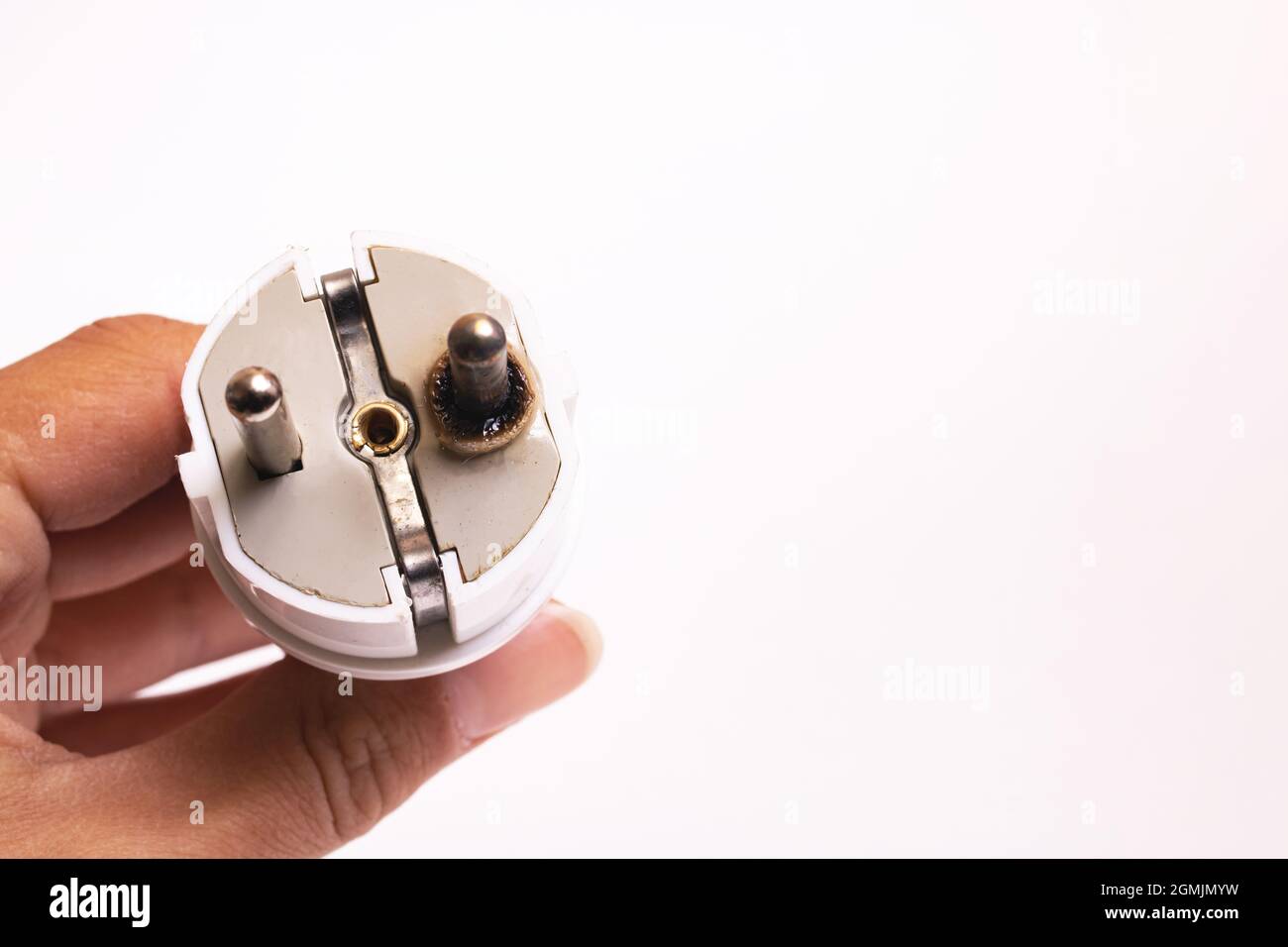 Burnt electrical plug in hand isolated on white background, copy space Stock Photo