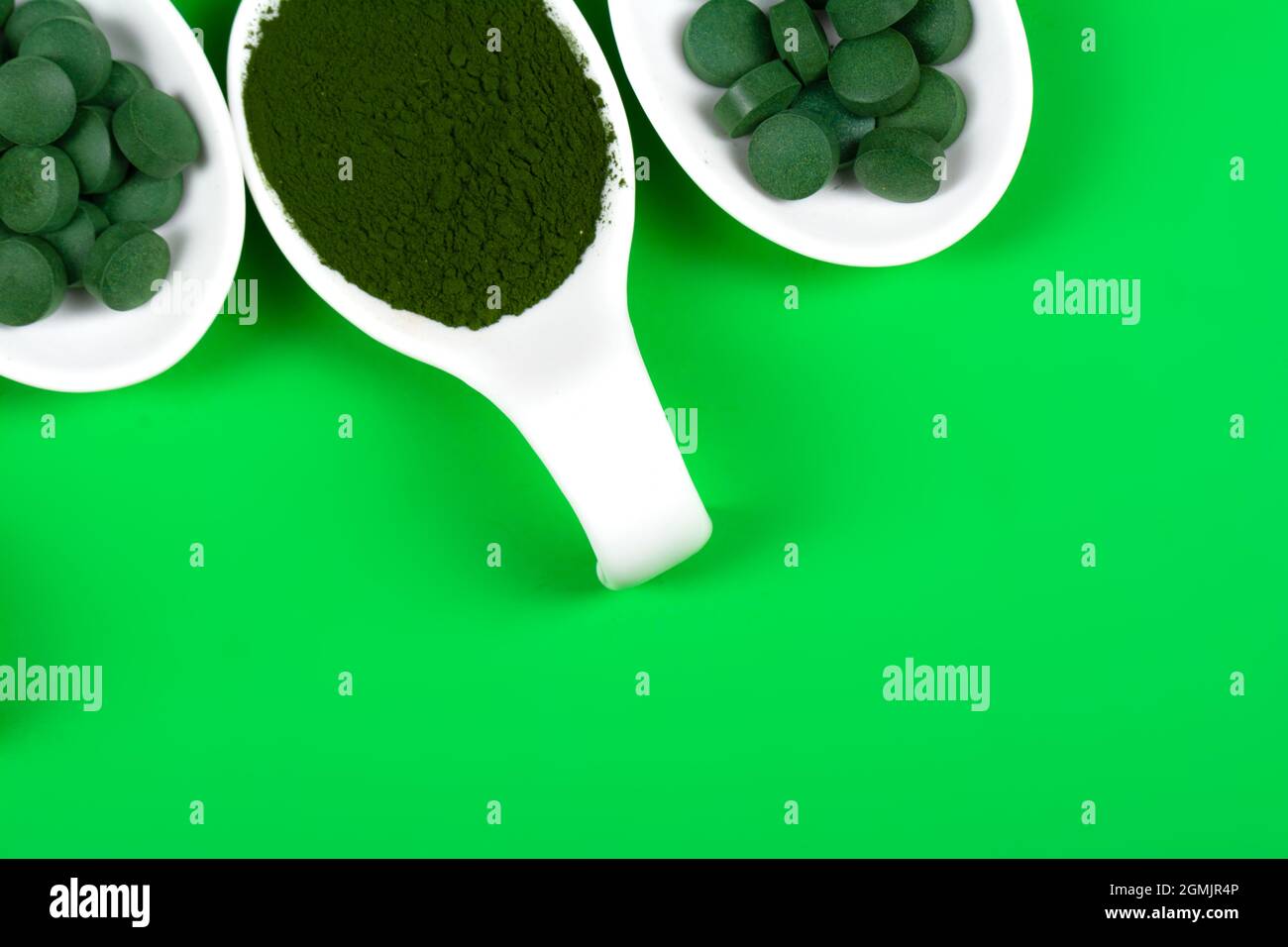 Chlorella or spirulina in the form of tablets and powder on a green  background, close up Stock Photo - Alamy
