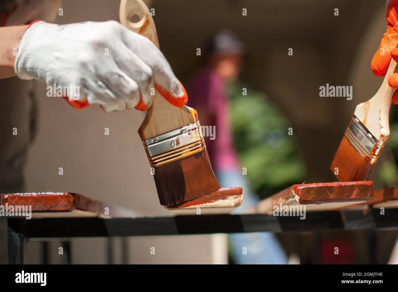 Female worker makes painting works of wooden products, plank with brown