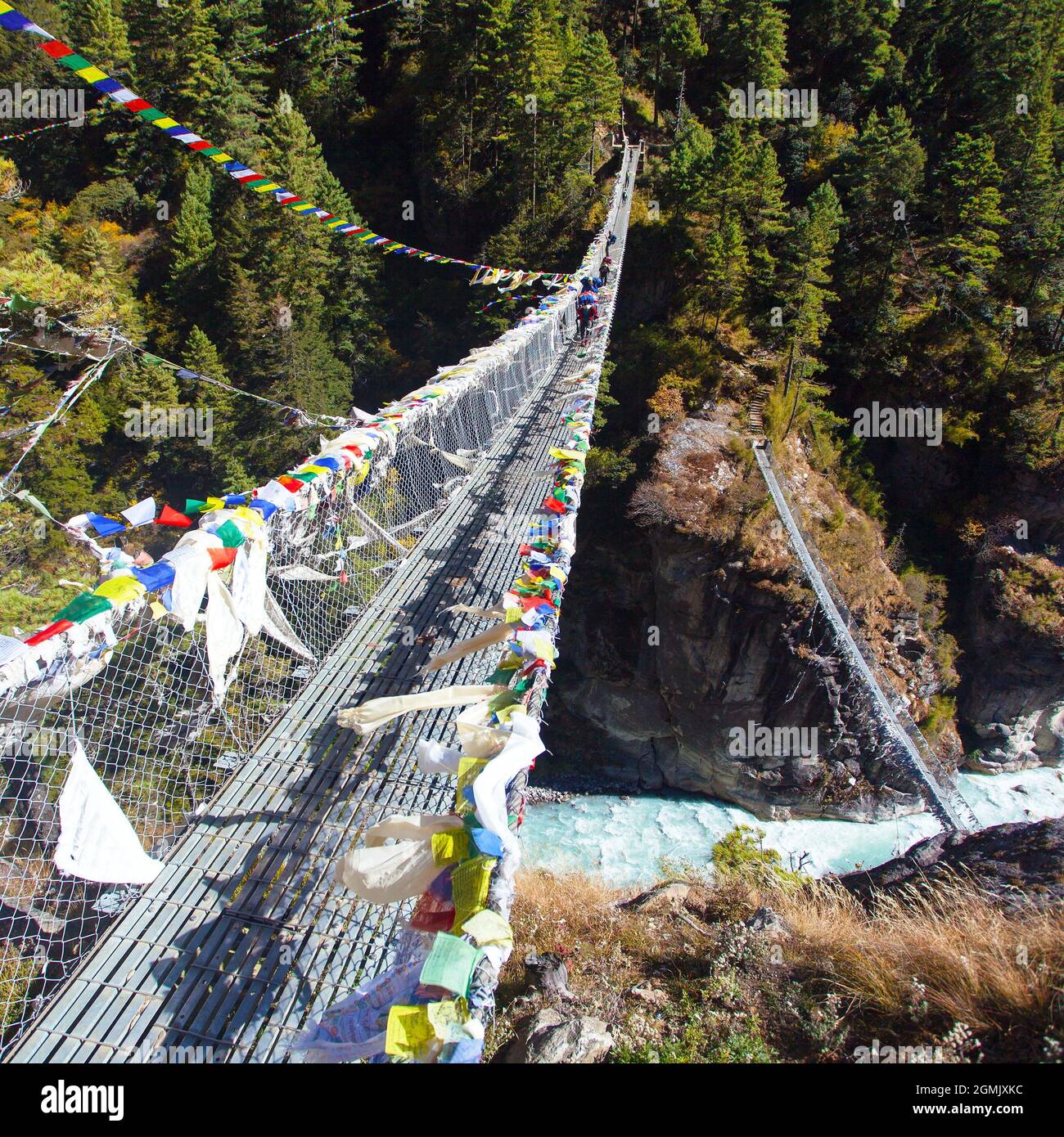 two rope hanging suspension bridge with prayer flags in Nepal Himalayas