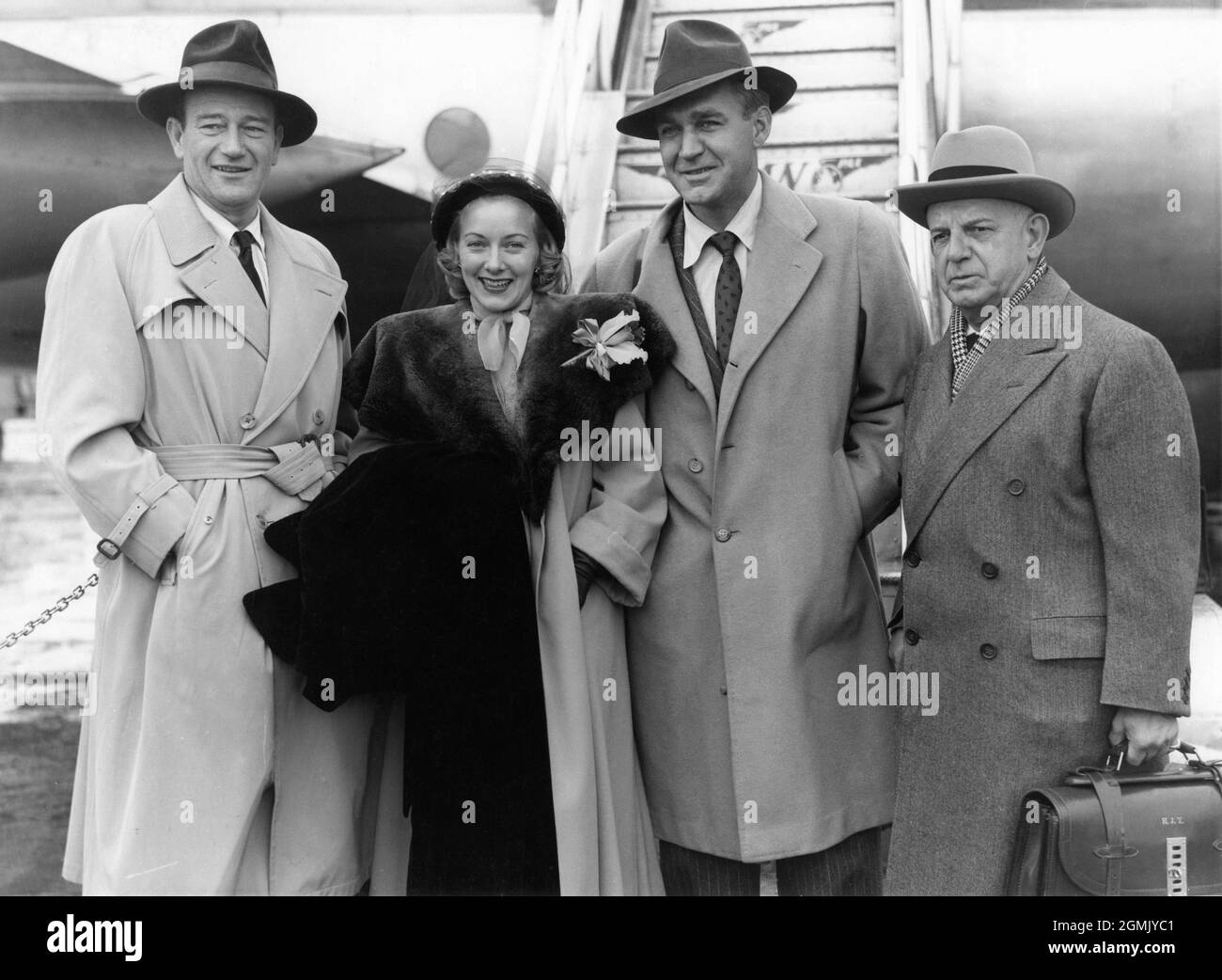 JOHN WAYNE and President of Republic Pictures HERBERT J. YATES (at right) with VERA RALSTON (who married Yates in March 1952) and FORREST TUCKER next to Pan Am Airplane following their arrival in London on Saturday 24th February 1951 to open new premises for Republic Pictures in Soho Square on the following Monday and attend the premiere of their latest film RIO GRANDE on Friday 2nd March at the Carlton Theatre publicity for Pan American World Airways Stock Photo