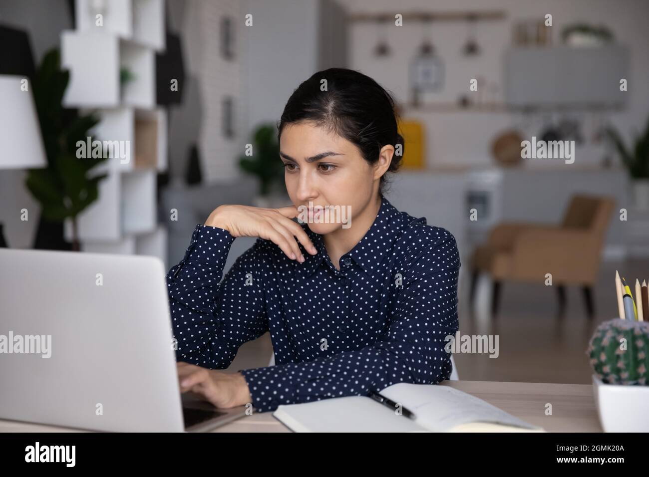 Confident Indian woman working on laptop, looking at screen Stock Photo