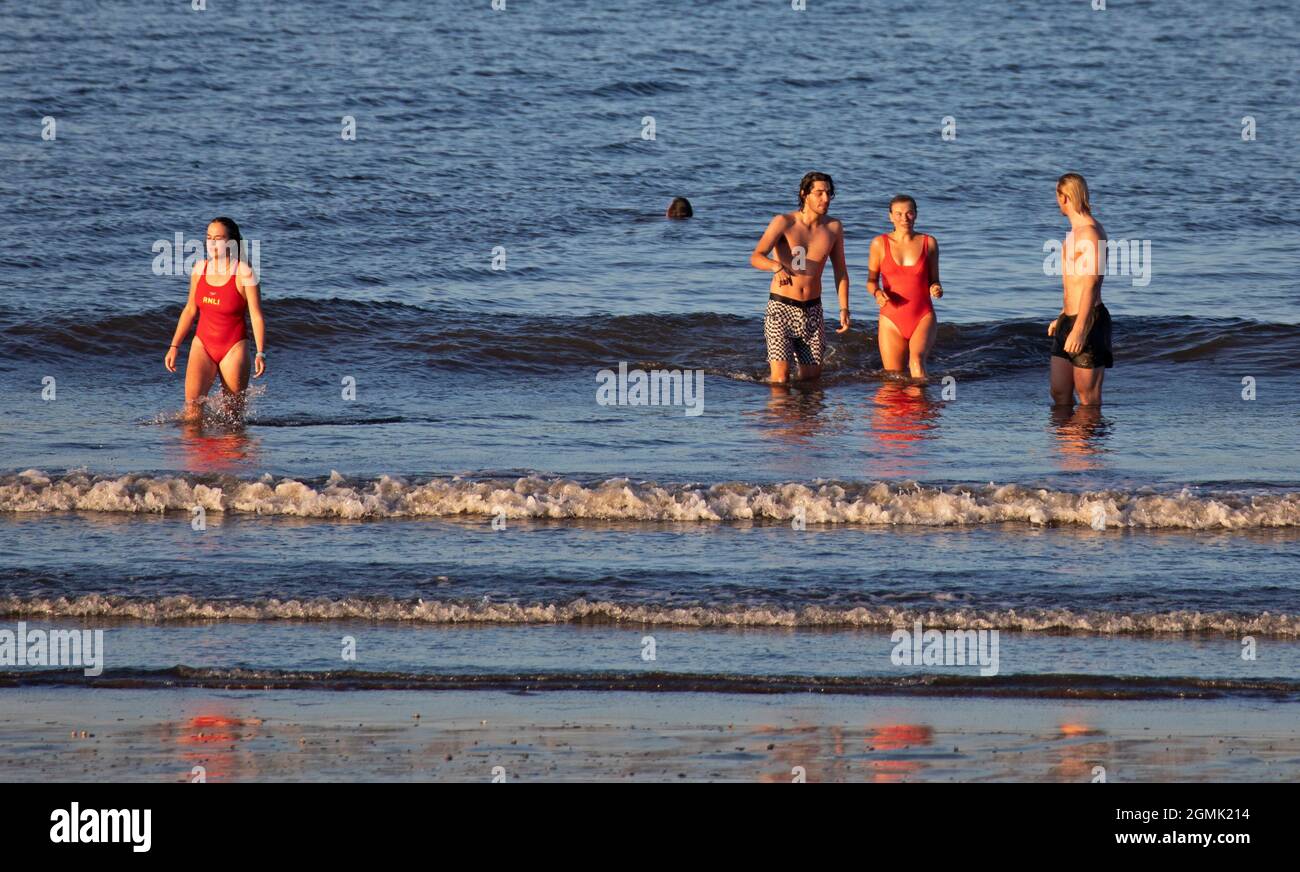 Portobello, Edinburgh, Scotland, Uk weather. 19th September 2021. Sunny evening shining warm light on this group of young people at the seaside on the Firth of Forth. Temperature 15 degrees centigrade. Credit: Scottishcreative/Alamy Live News. Stock Photo