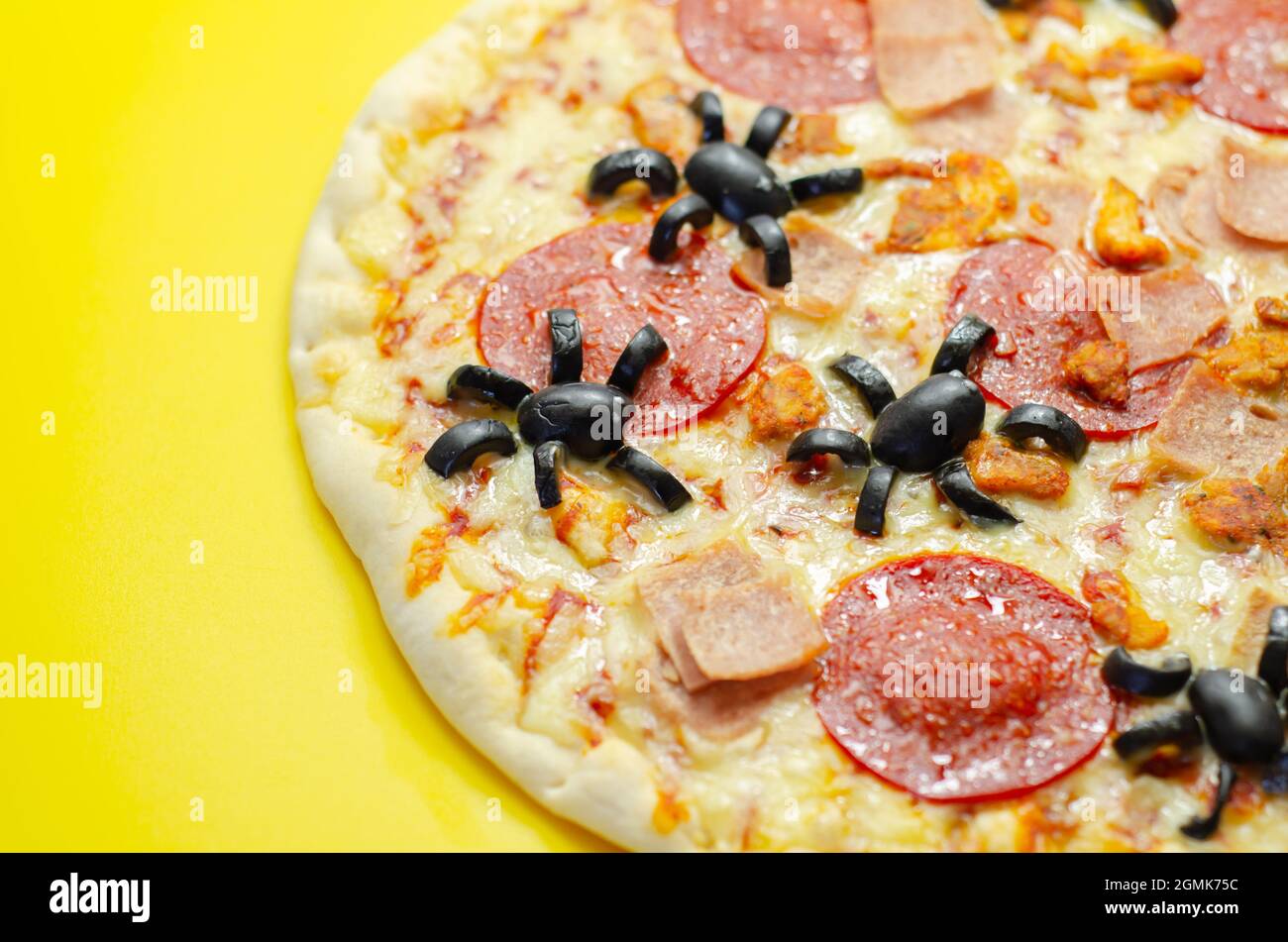 Meat feast pizza on thin dough decorated with black olives in the shape