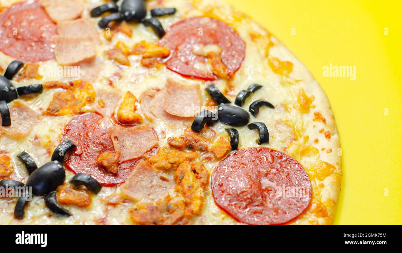 Meat feast pizza on thin dough decorated with black olives in the shape