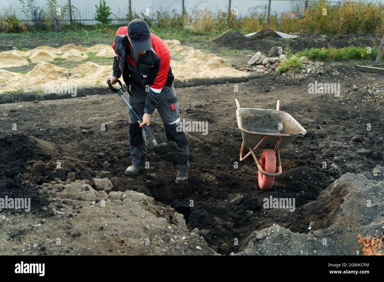 Working with garden tools, shovel and wheelbarrow on the site of a country house. Preparation for construction work. Stock Photo