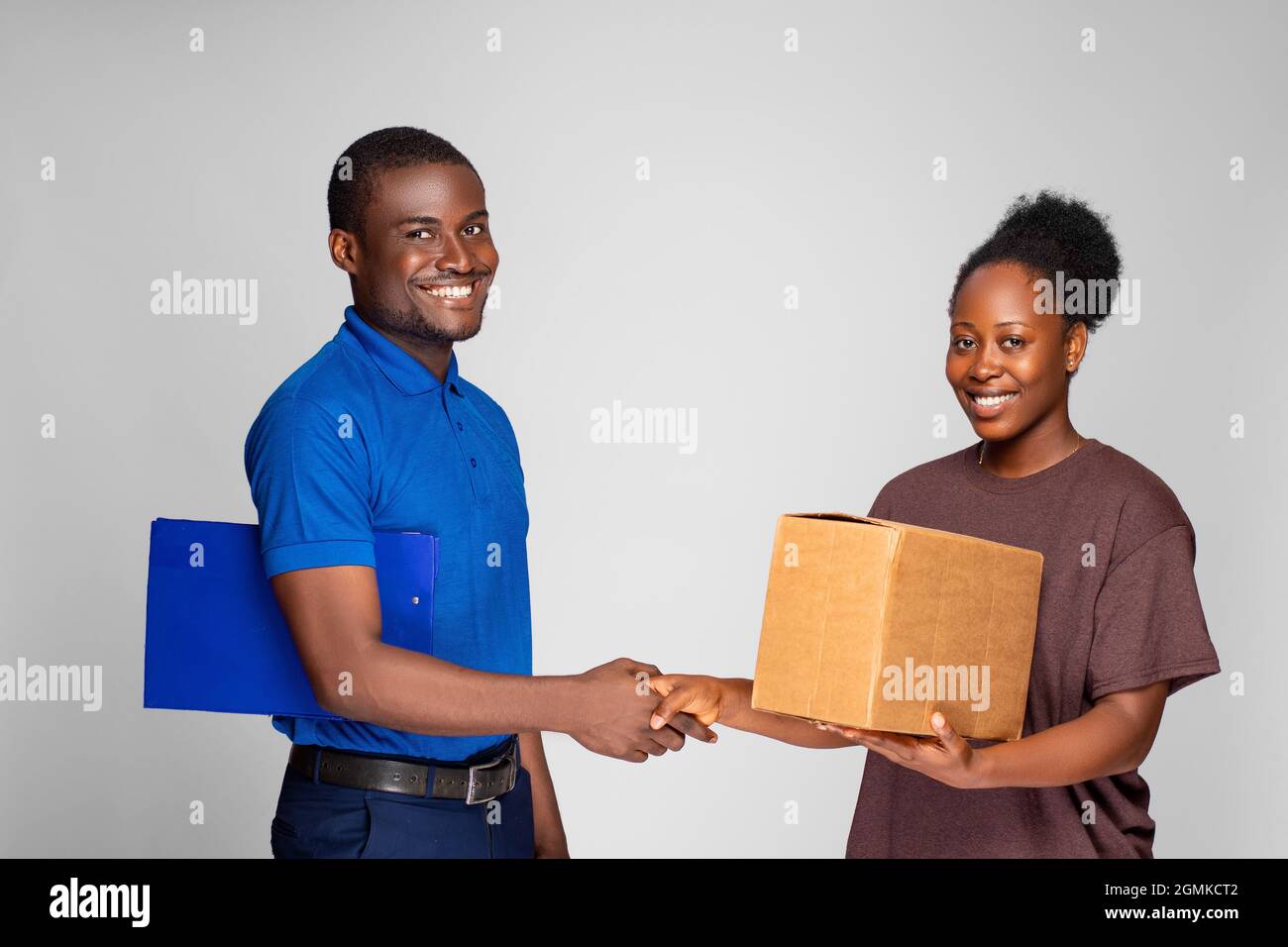 black woman shakes had with a delivery worker after receiving a package Stock Photo