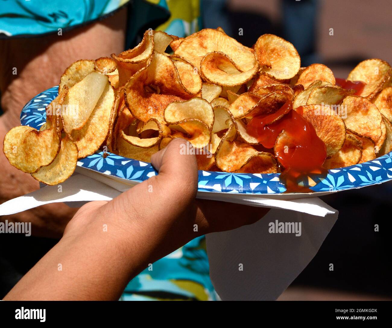A customer adds tomato catsup to a plate of ribbon fries purchased from