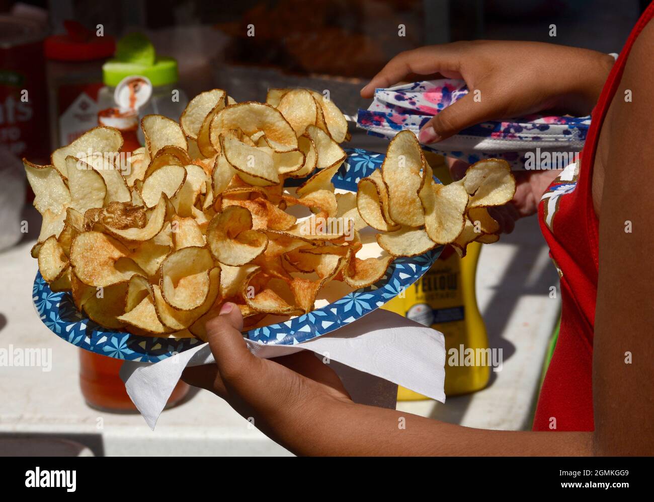 A customer adds tomato catsup to a plate of ribbon fries purchased from