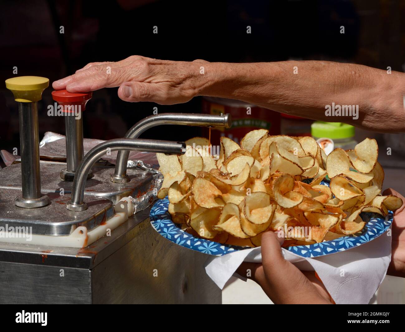 A customer adds tomato catsup to a plate of ribbon fries purchased from