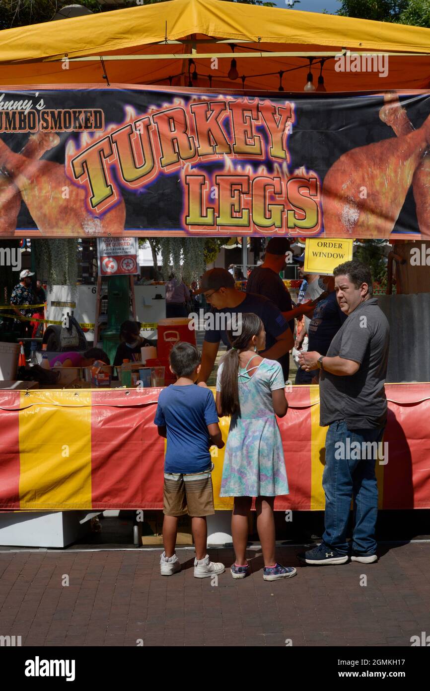 Customers purchase smoked turkey legs from a food vendor at the annual Fiesta de Santa Fe in Santa Fe, New Mexico. Stock Photo