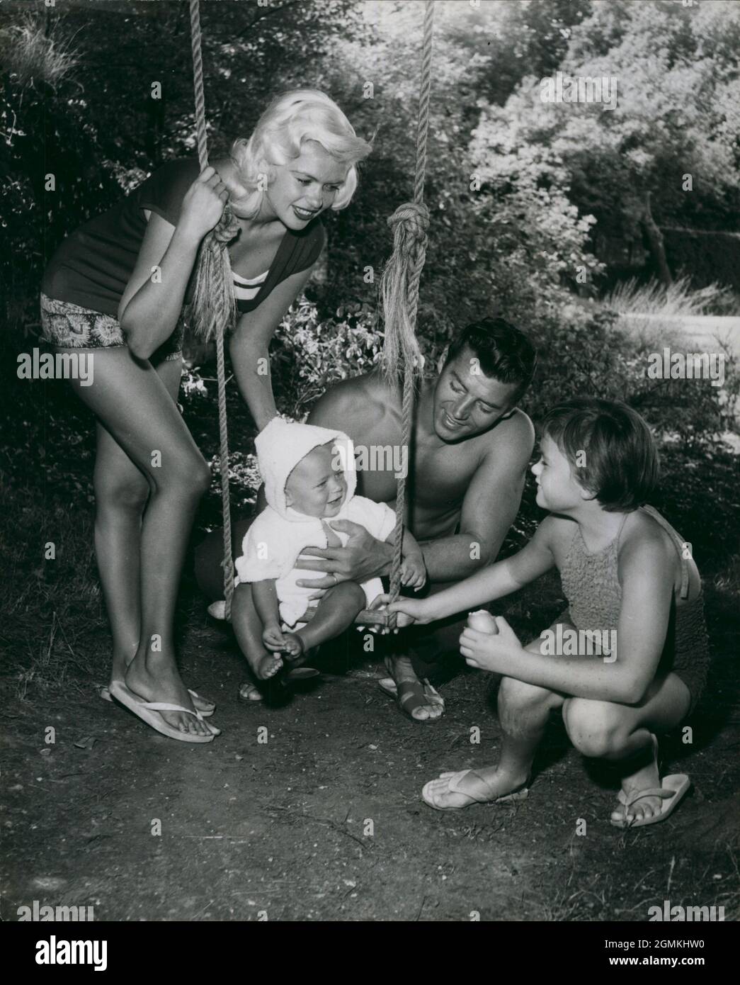 1959 - Garrads Cross, England, United Kingdom - On the swing, Baby MIKLOS HARGITAY gets encouragement from the whole family as he prepares to embark on his first swing. Actor JAYNE MANSFIELD, left, her husband MICKEY HARGITAY, their new arrival, baby Miklos, and Mansfields daughter from her first marriage JAYNE MARIE, right, moved into the 18 the century country home of actor H. Gregg while Mansfield played her part in a film tiled ''Too Hot to Handle'' being made here.  (Credit Image: © Keystone Press Agency/ZUMA Wire) Stock Photo
