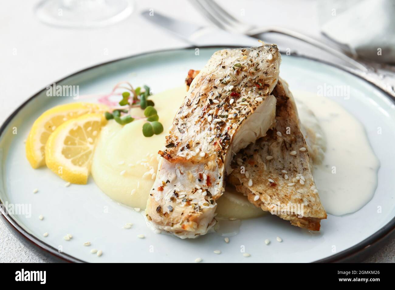 Plate with baked cod fillet, sauce and mashed potatoes on table in ...