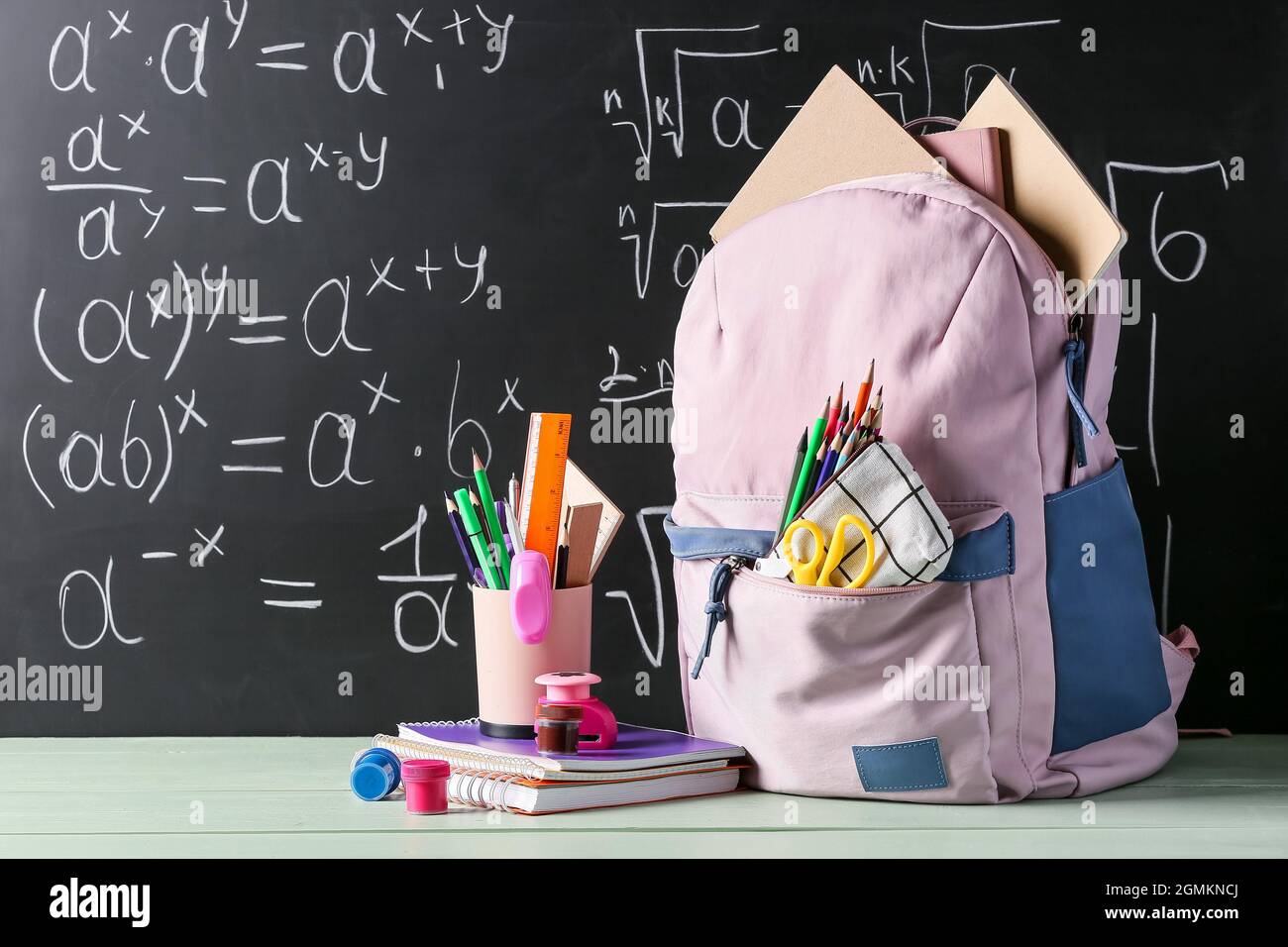 School backpack and stationery on table in classroom Stock Photo