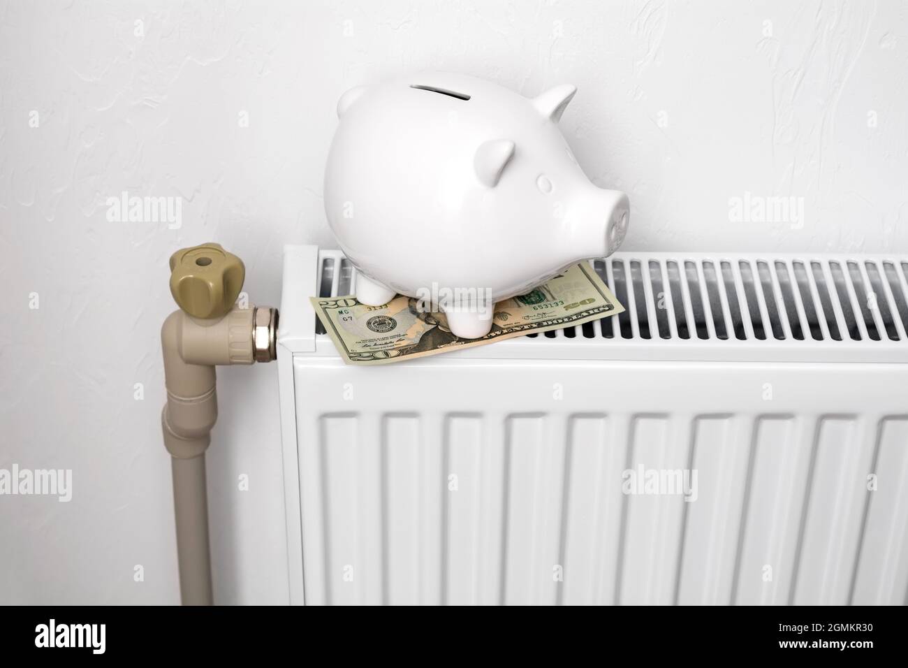 White pig piggy bank on radiator. Expensive heating costs concept. Stock Photo