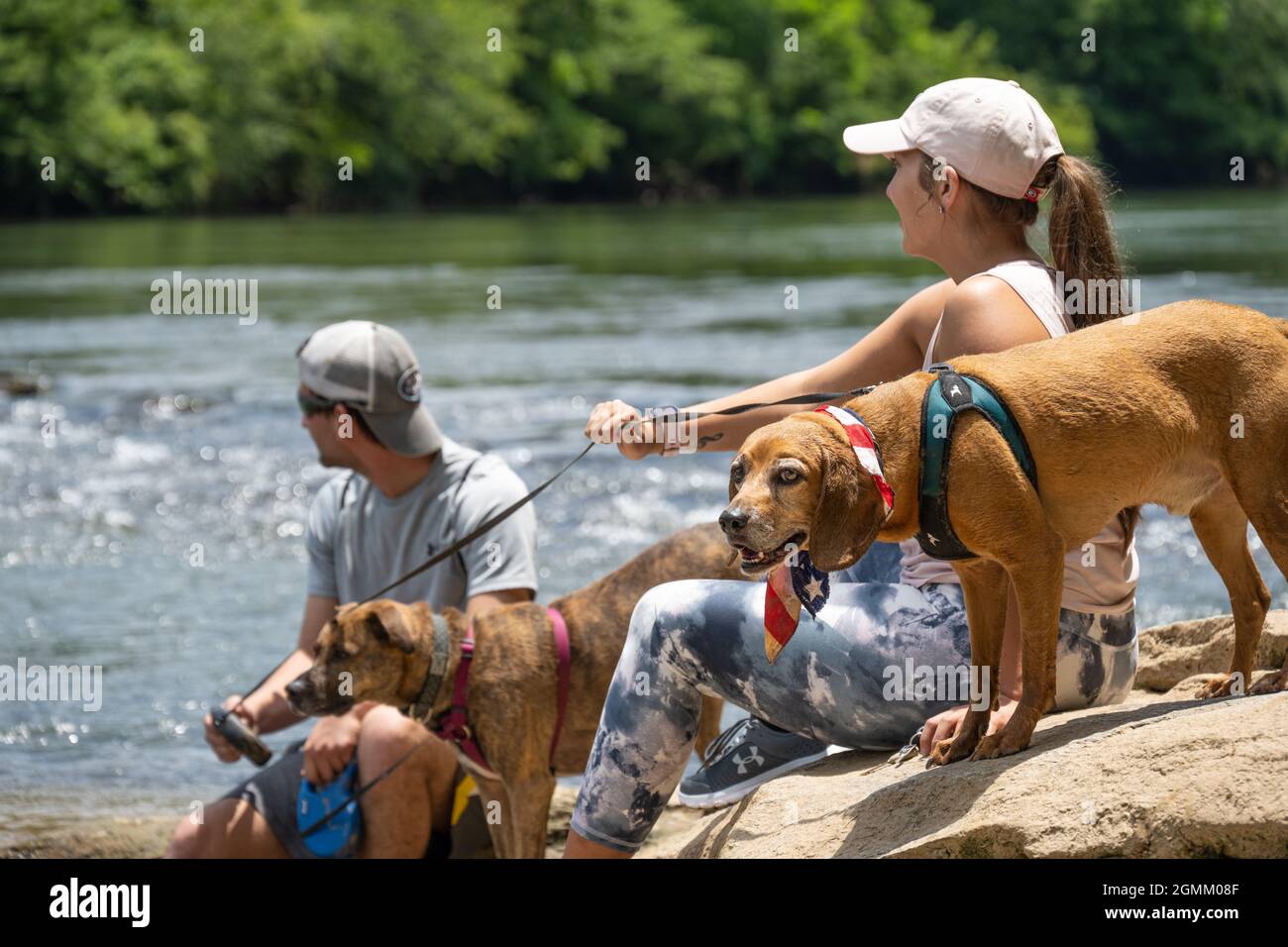 Couple with dogs relaxing along the rocky shoreline of the Chattahoochee River in Sandy Springs, just north of Atlanta, Georgia. (USA) Stock Photo